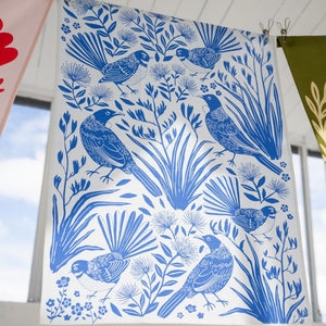 100%NZ Birdsong Blues Tea Towel pegged to a clothes line with other tea towels in the same range.