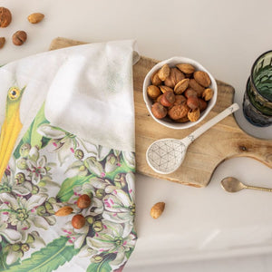 100%NZ Birds & Botanicals Heron Tea Towel draped across a wooden chopping board in a kitchen scene.
