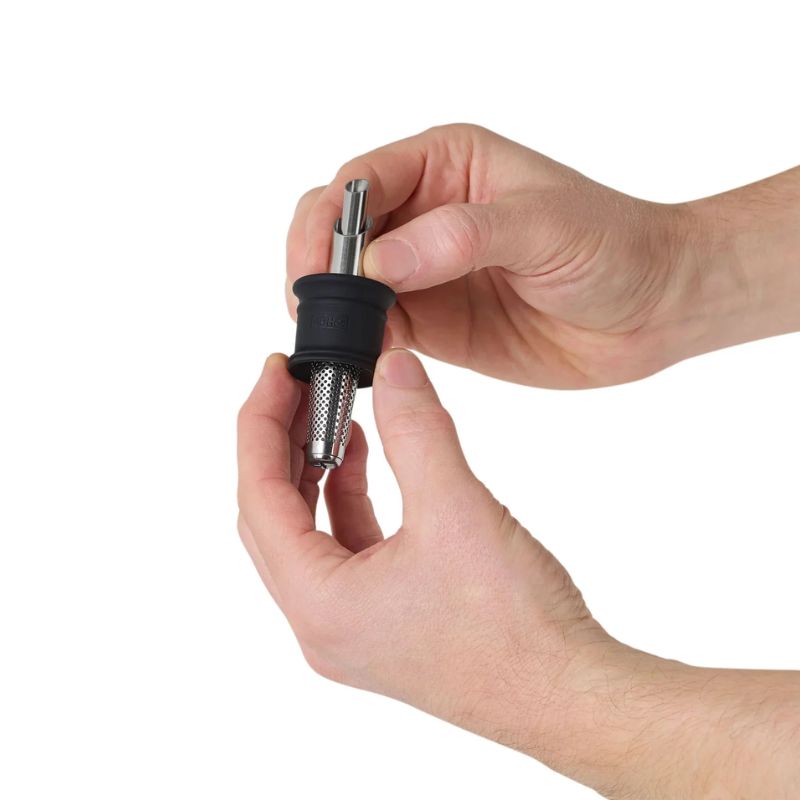 Hands holding the stainless steel spout and filter component for the AdHoc oil and vinegar dispenser