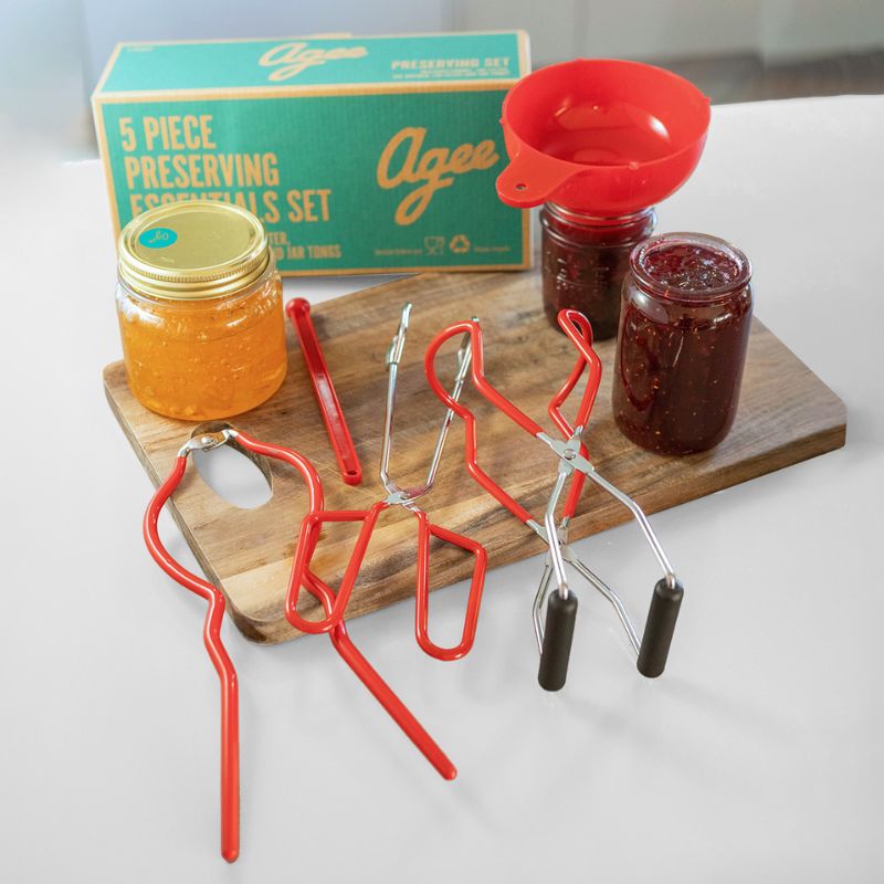 A set of five red kitchen utensils for preserving, including a funnel, jar lifter, jar wrench, magnetic lid lifter, and canning tongs – Agee Preserving Accessory Set.