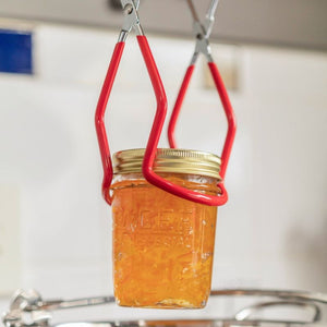 Agee jar lifter being used to lift a jar of marmalade out of a preserving pan.