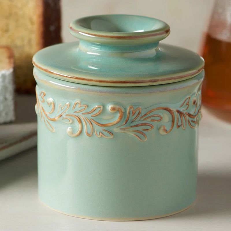 Close up view of the Antique Sea Spray Butter Bell Crock showing embossed vine and leaf detail and soft sea-blue glaze