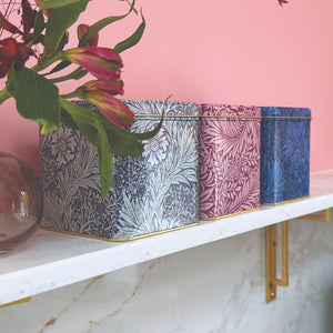 Arts & Crafts Marigold Square Tin Caddies styled on a marble shelf against a pink wall.