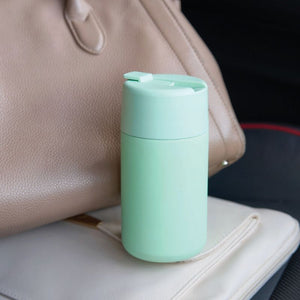 Avanti Brew Insulated Travel Cup in Soft Mint on a car seat next to a beige handbag.