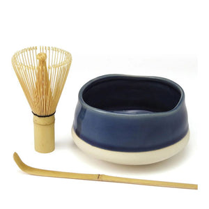 Avanti Matcha Ceremonial Set featuring a bamboo whisk, a dark blue ceramic bowl with a beige base, and a bamboo scoop on a white background.