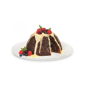 Steamed fruit pudding with custard and berries on a white plate.
