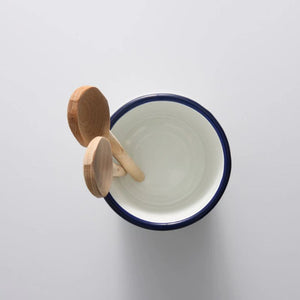 Bakemaster Enamel Utensil Holder with blue rim and wooden spoons on a light gray background