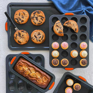 Various Bakemaster Silicone baking pans with baked goods including muffins, cupcakes, and a loaf on a gray surface.