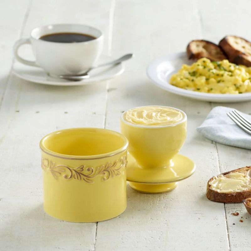 Goldenrod yellow Butter Bell Crock with embossed vine design, shown on a white background