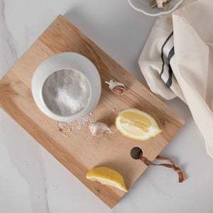 The White Casafina Fattoria Salt Pig/Cellar displayed on a wooden chopping board with garlic and lemons.