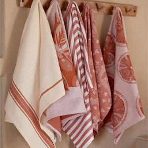 Assortment of orange Casafina kitchen towels having from hooks in a kitchen