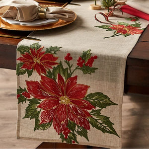 Design Imports Christmas Table Runner – Poinsettia & Holly styled on a wooden table with a gold plate and napkins.