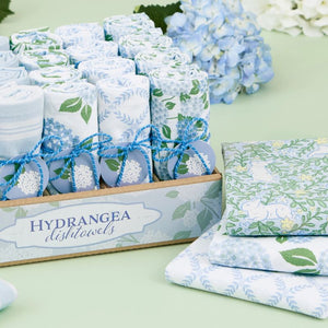 Packaged tea towels with floral design on a light green surface.