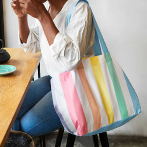 Woman sitting in cafe with Dock & Bay Foldaway Tote Bag - Unicorn Wave | NZ
