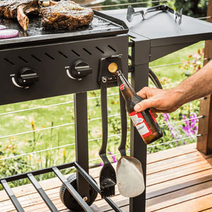 Hand removing cap from bottle using the bottle opener on the holder of Dreamfarm BBQ Grill Tools Set.