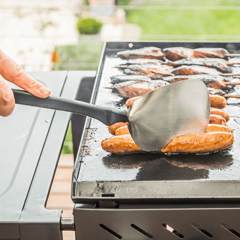 Dreamfarm BBQ Chopula being used to chop sausages on a barbecue.