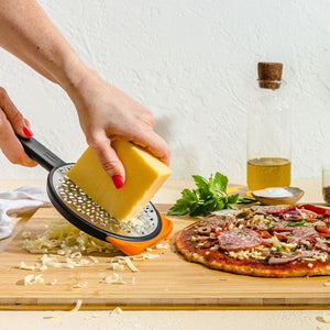 Woman using Dreamfarm Ograte Coarse Grater to grate cheese for a pizza.