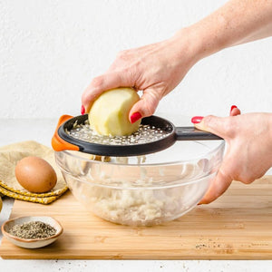 Dreamfarm Ograte Coarse Grater hooked over a bowl being used to grate a potato in circular motion | NZ