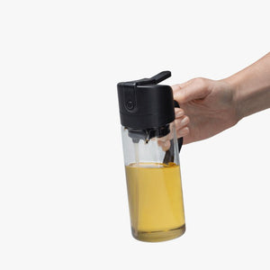 Person holding the Dreamfarm Oileroo – Oil Sprayer & Pourer on a white background.