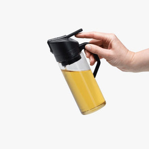 Person holding the Dreamfarm Oileroo – Oil Sprayer & Pourer on a white background.