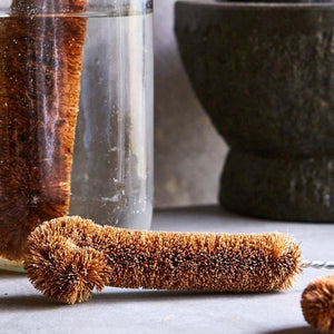 Coconut fibre bottle brush on bench top with kitchen items behind