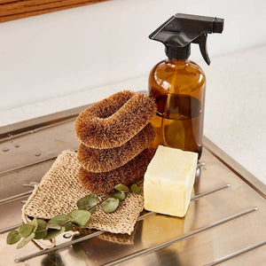 Stack of Eco Max Kitchen Scrubbers next to a soap bar, bench spray and natural dish cloth on a kitchen bench top