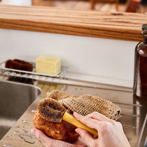 Eco Max Veggie Brush at a stainless steel sink scrubbing a potato