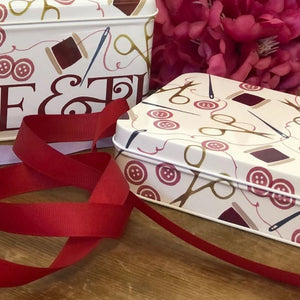 Emma Bridgewater Crafting tin collection shown next to red ribbon and flowers.