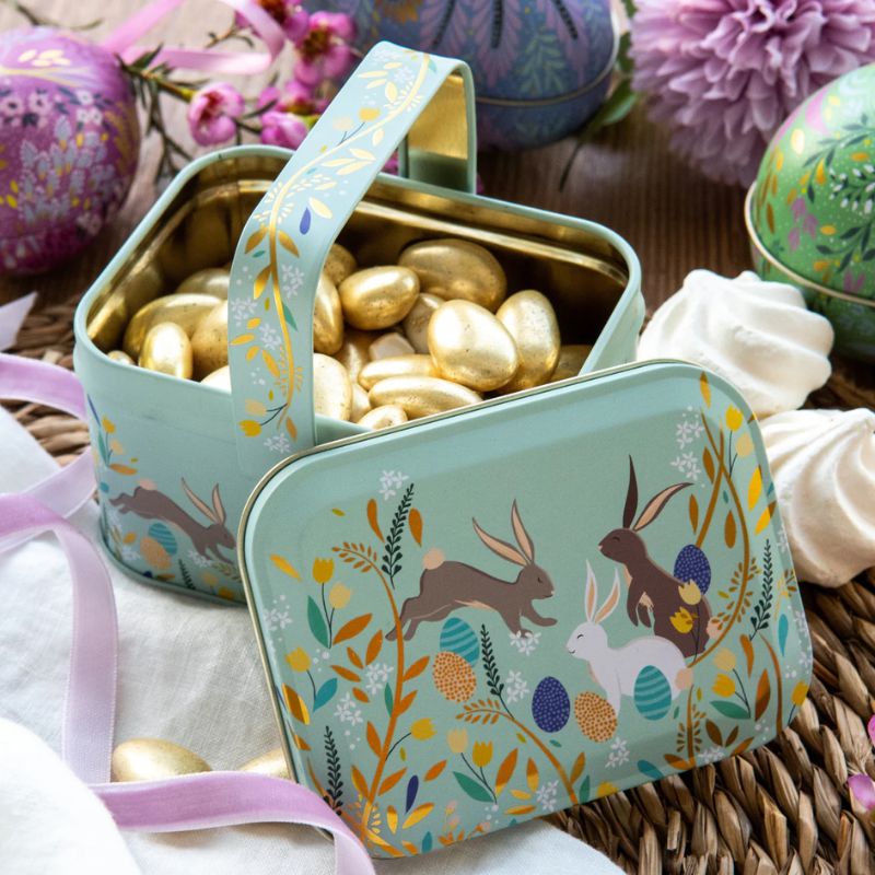 Sara Miller Happy Bunnies Easter Handle Basket, illustrated with rabbits, flowers and pastel eggs on a soft blue background.