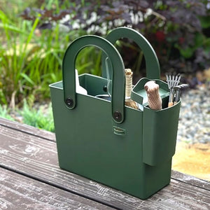 Hachiman Garden Tool Bag with Pocket in a garden setting shown with a variety of items in the main tote back and removable pocket