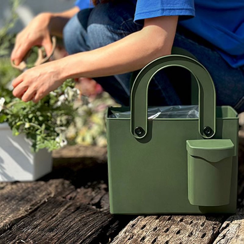 Close up of the Hachiman Garden Tool Bag with Pocket with women crouched behind cutting herbs from a garden