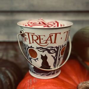 Halloween decorations and supplies NZ featuring a trick or treat candy bucket filled with sweets on pumpkins.