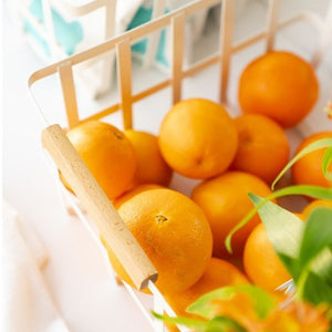 Close-up of wooden handle on white metal basket; oranges inside the basket.