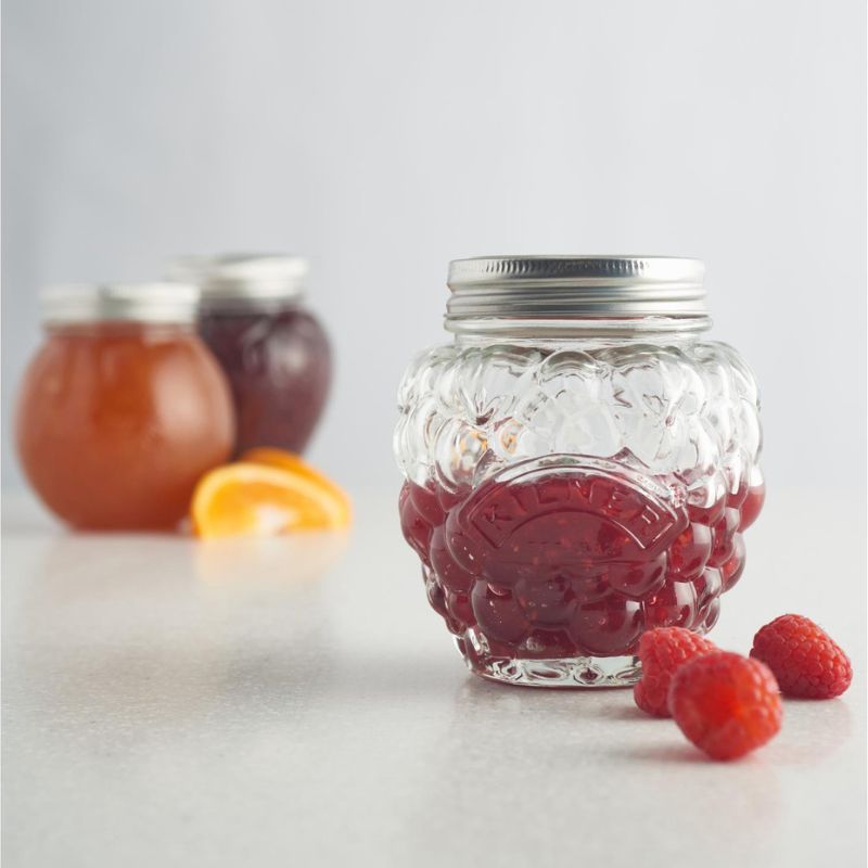 Kilner Berry Fruit Preserve Jar filled with raspberry jam, displayed with fresh fruit on a white background.