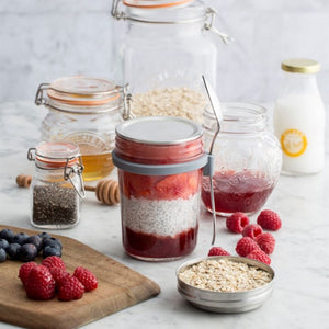Kilner Breakfast Jar filled with layers of oats, yoghurt, and fruit, shown with fresh berries and ingredients on a kitchen bench.