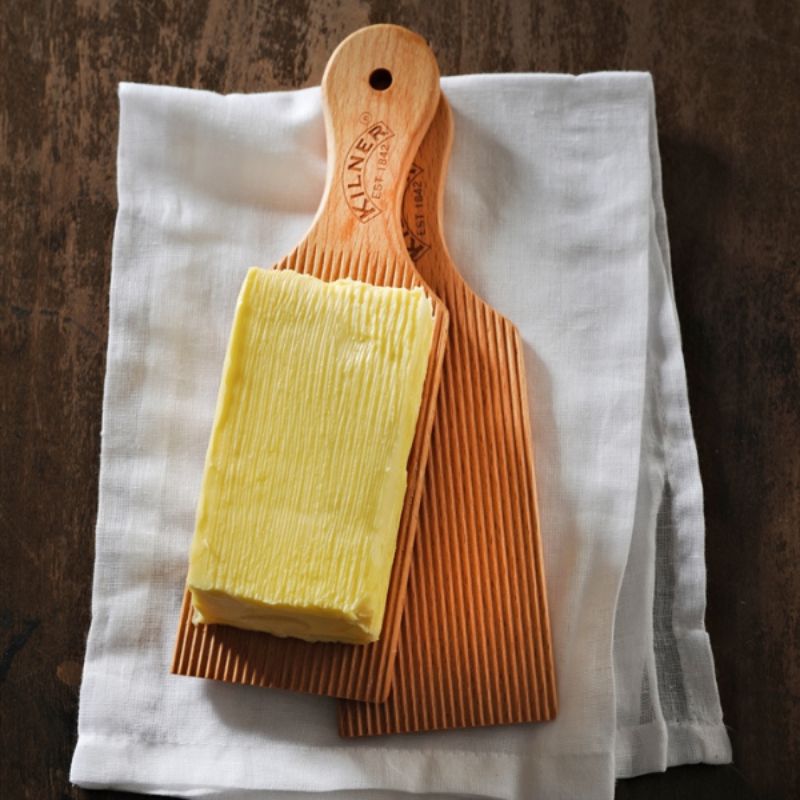 Pair of Kilner wooden butter paddles with grooved surfaces, placed side by side on a white background.