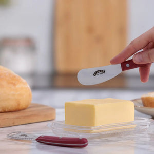 The Kilner butter spreader being used to get butter from a block with a blurred kitchen background.