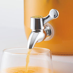 Tap on drinks dispenser shown open with orange juice filling a glass
