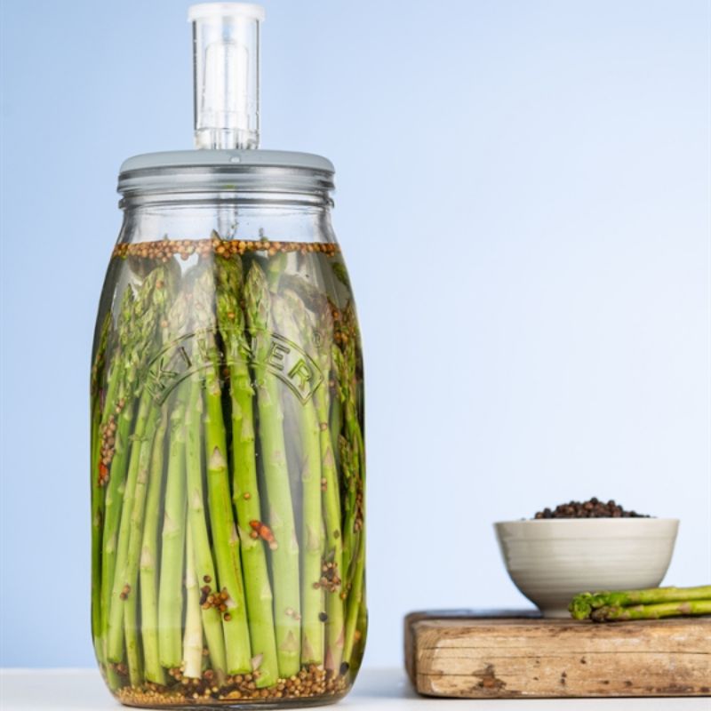 3L Kilner glass fermentation jar filled with asparagus shown beside a wooden chopping board