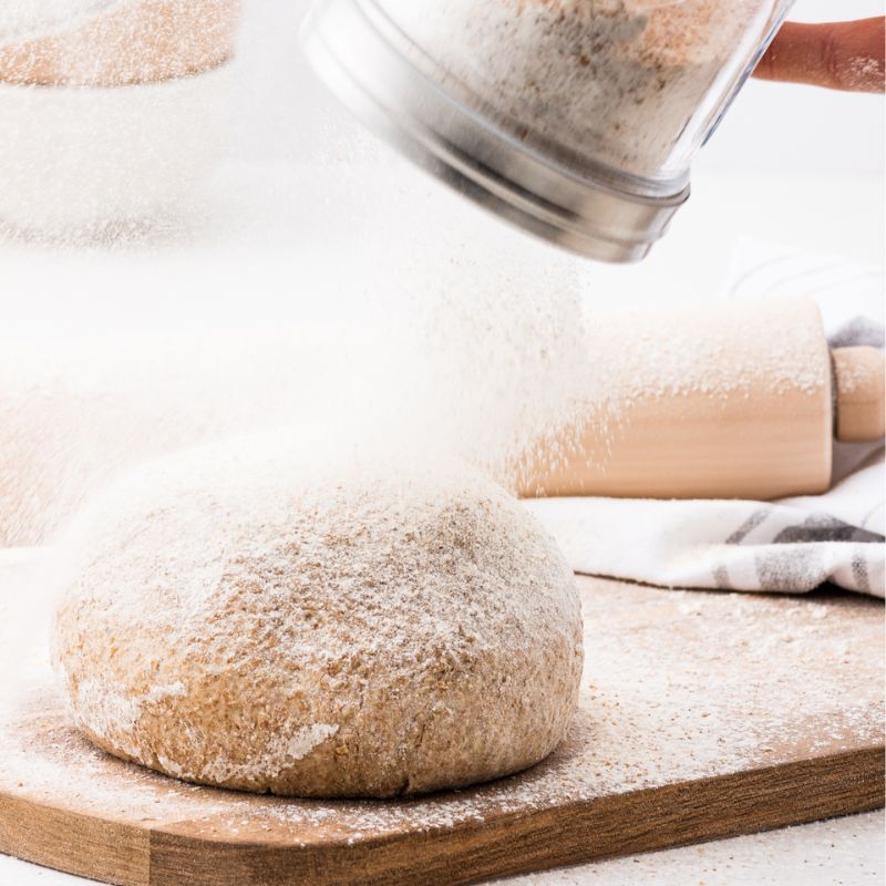Kilner Sifter Jar dusting flour over dough on a wooden board.