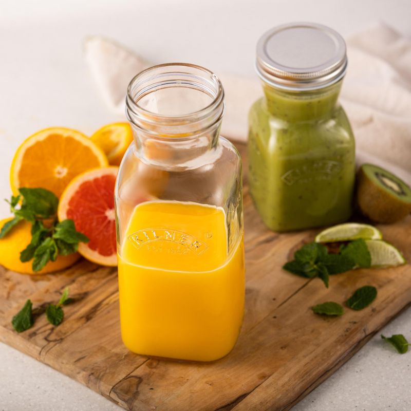 Kilner Juice & Sauce Bottle filled with orange juice, surrounded by fresh fruit and green smoothie.