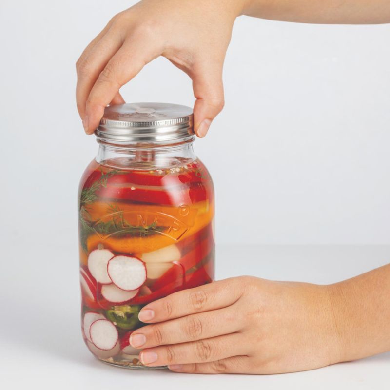 Air-lock / pressure-release lid being applied to a Kilner regular mouth jar filled with vegetables and a glass weight - Fermentation starter kit NZ