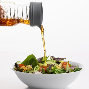 Kilner Salad Dressing Maker pouring dressing over a salad, shown against a white background.