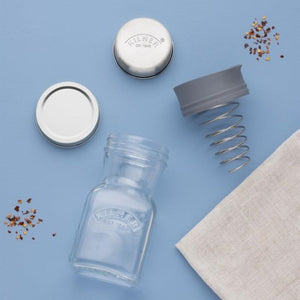 Kilner Salad Dressing Maker styled on a light blue background with chilli flakes.