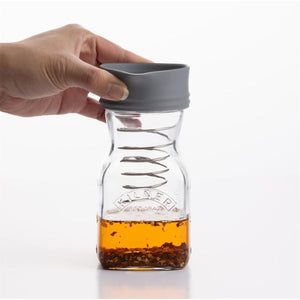 Person putting the lid on the Kilner Salad Dressing Maker, shown against a white background.