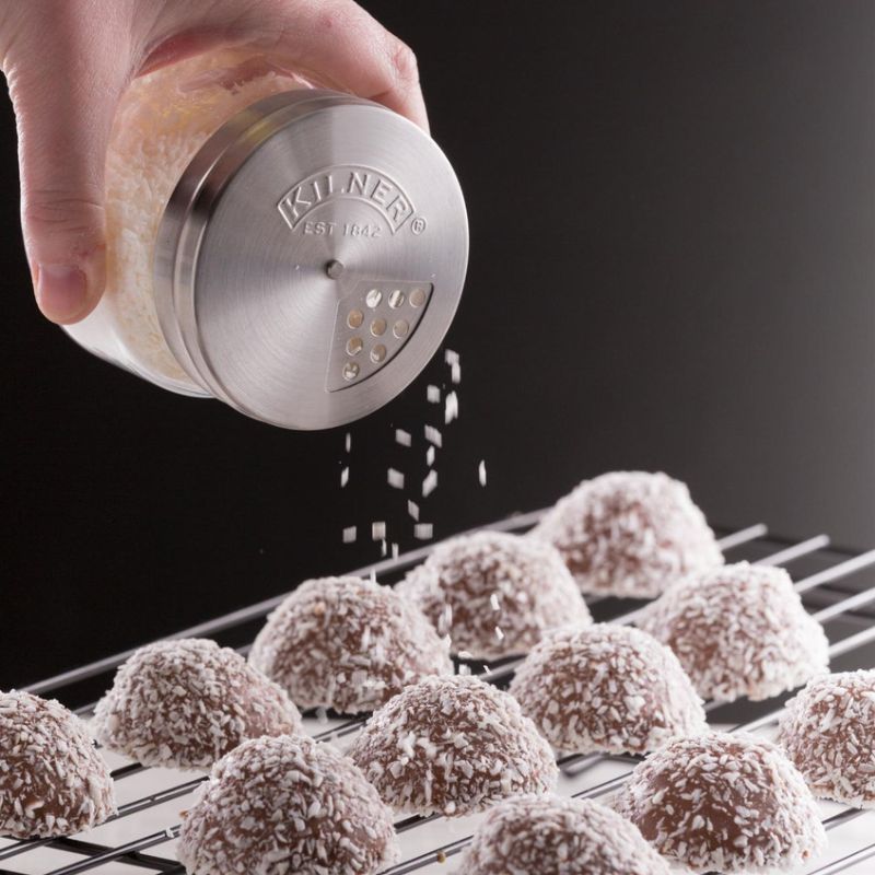Kilner shaker jar dusting coconut over macaroons on a cooling rack.