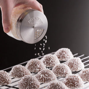 Kilner shaker jar dusting coconut over macaroons on a cooling rack.