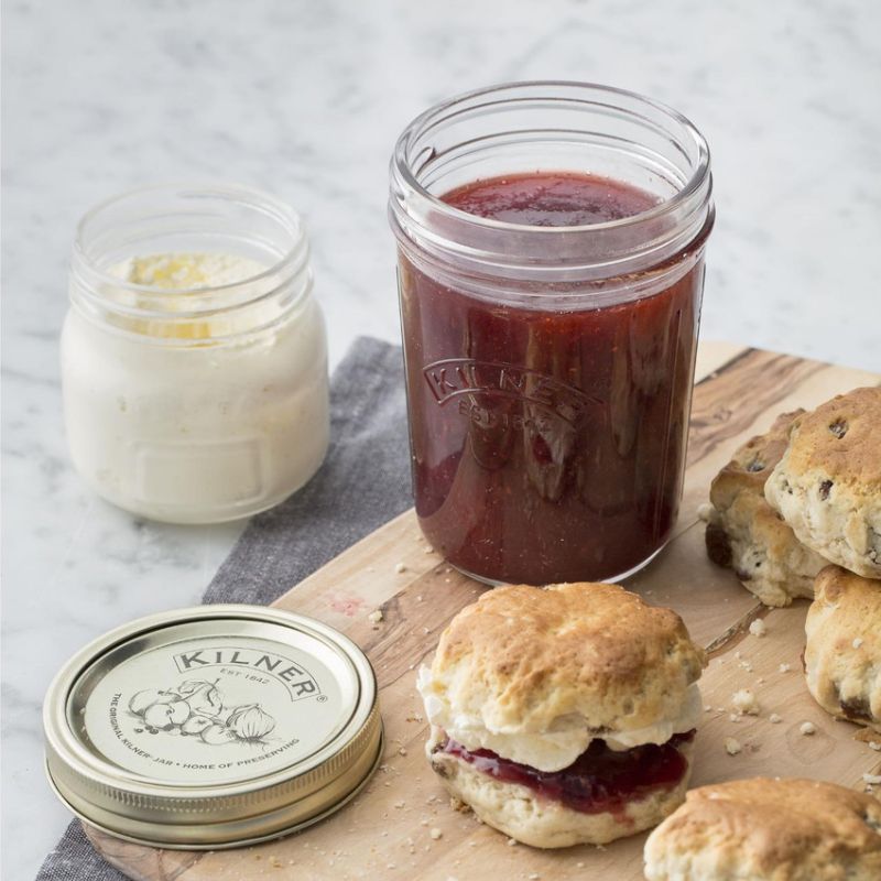 Strawberry jam in the 350mL Kilner Wide Mouth Preserve Jar shown with a jar of cream and scones on a wooden chopping board