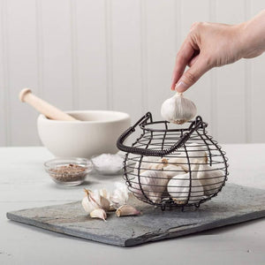 Hand placing garlic bulb into Kilo Traditional Garlic Basket | NZ