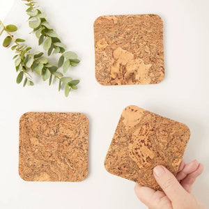 Hand holding a Liga natural cork coaster.